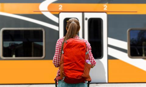 Ung kvinna med ryggsäck reser med tåg 