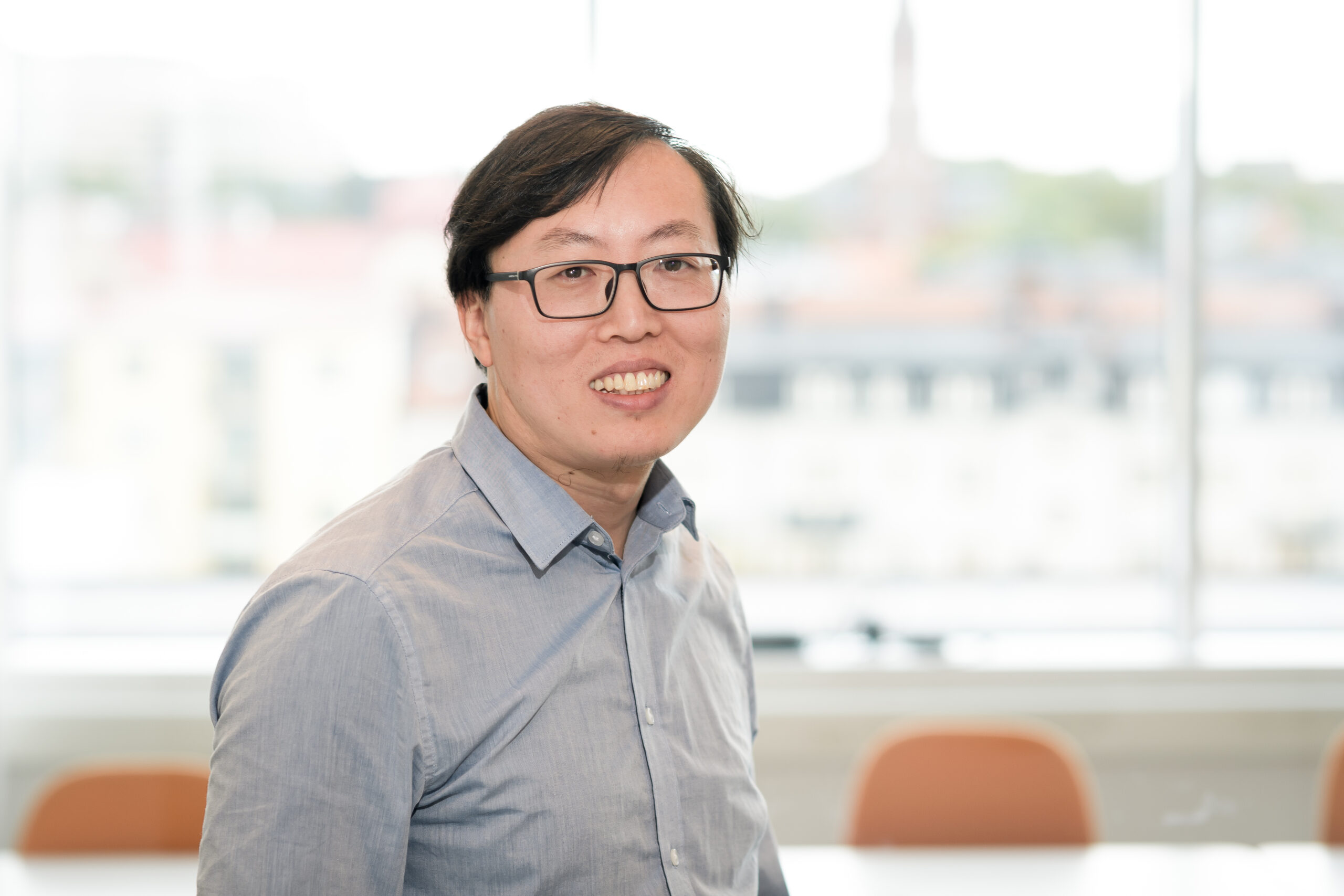 Porträttbild på Pengxiang Zhao mot en suddig bakgrund i kontorsmiljö.