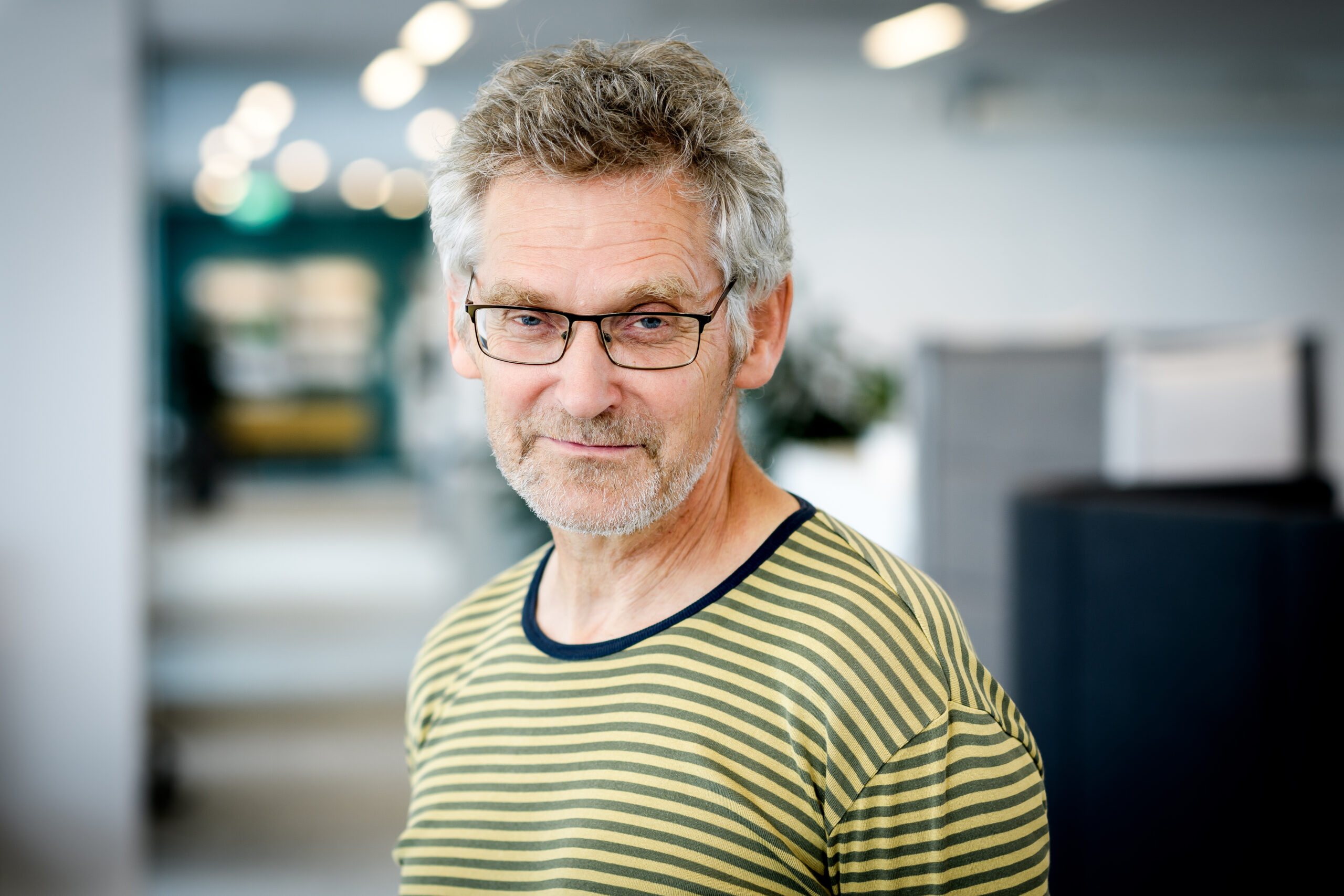 Porträttbild på Claus Hedegaard Sørensen mot en suddig bakgrund som visar en kontorsmiljö.