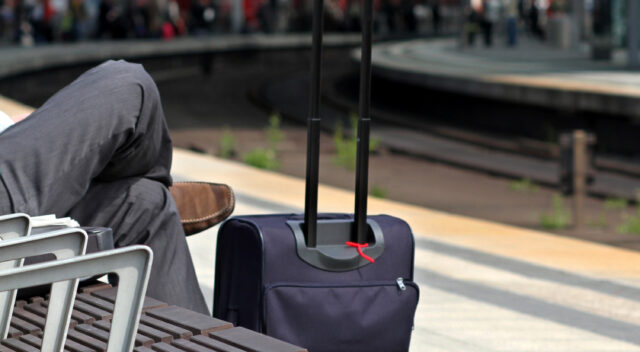 Resenär väntar med väska på en station. Foto.