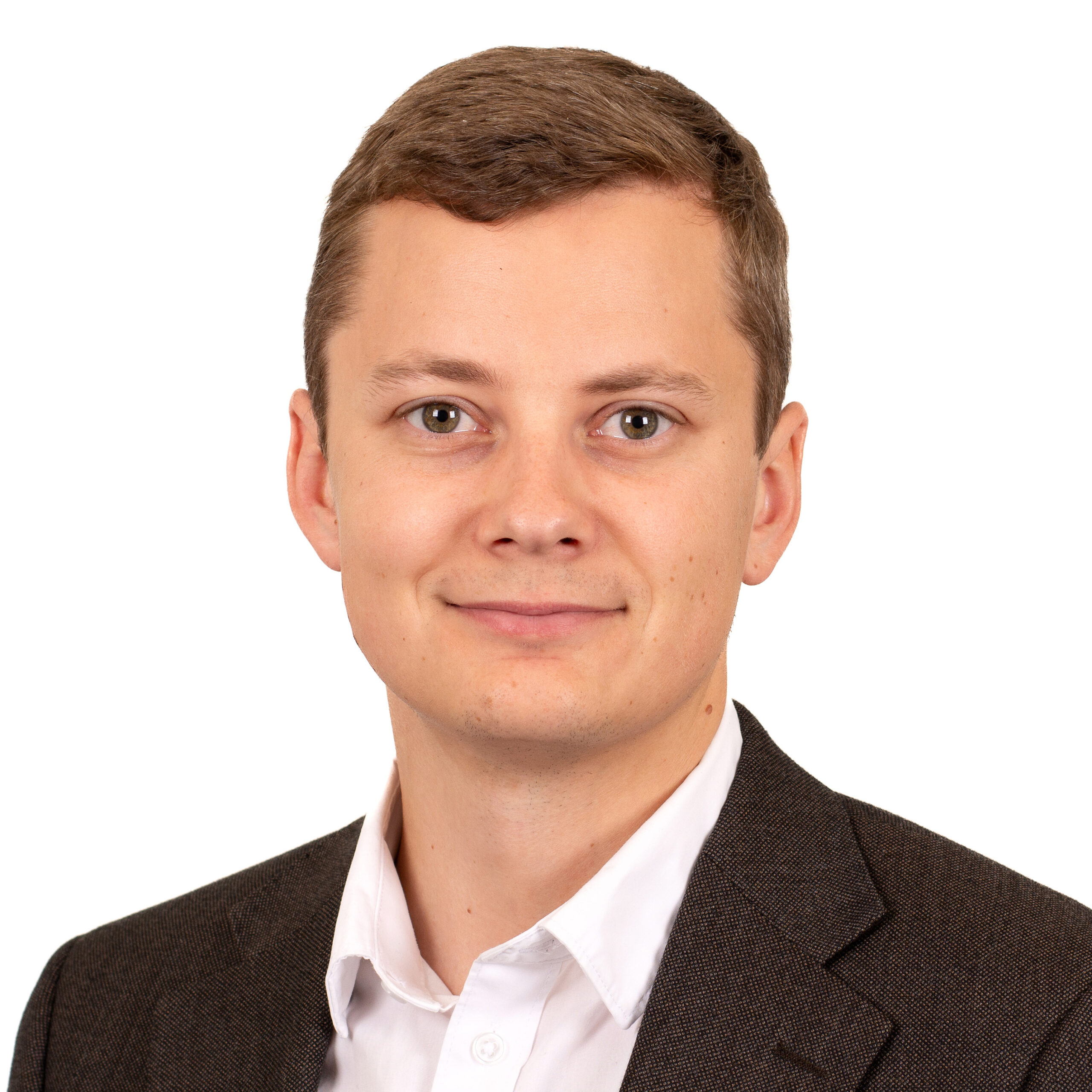 En man med kort brunt hår, mörk kavaj och vit skjorta. Foto.