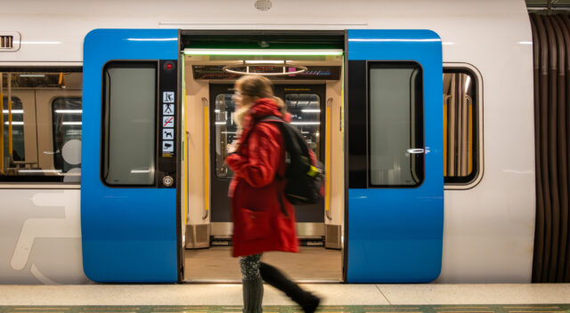 Kvinna som går förbi öppna tunnelbanedörrar. Foto.