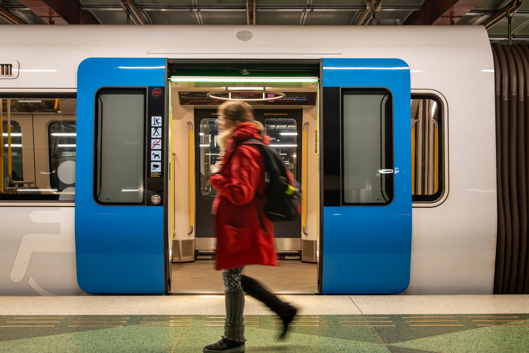 Kvinna som går förbi öppna tunnelbanedörrar. Foto.